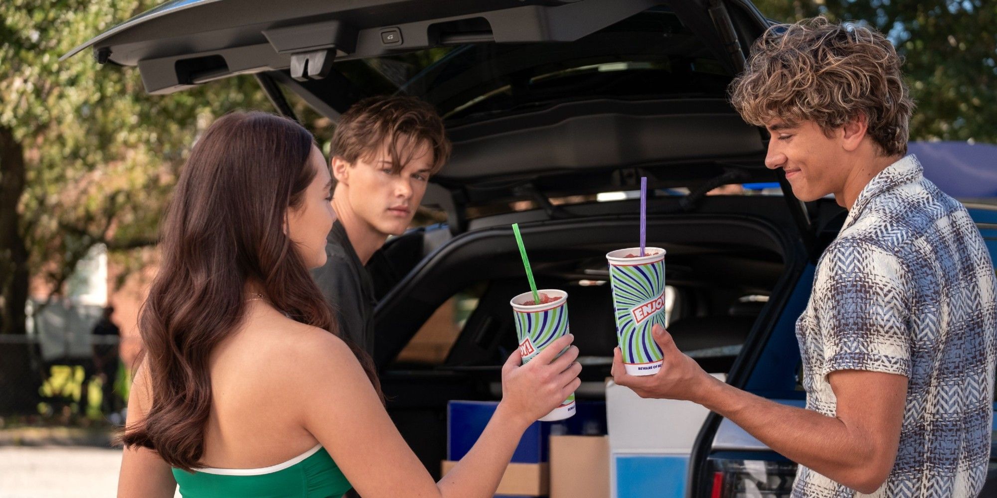 Belly Conklin and Jeremiah Fisher drinking slushees in front of Conrad Fisher in 'The Summer I Turned Pretty' Season 2.