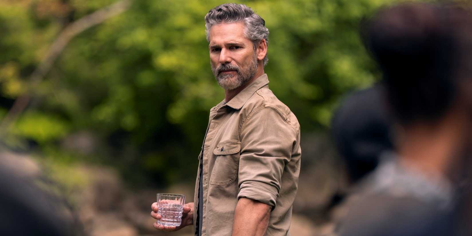 Eric Bana sebagai Kyle Turner memegang minuman di tangannya sambil berdiri di hutan Yosemite di Untamed