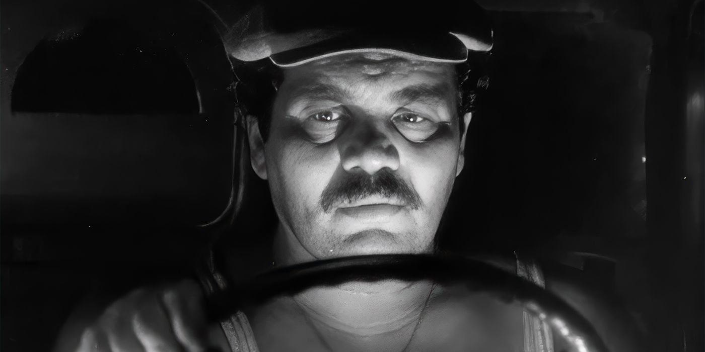 Luigi, played by actor Fulco Lulli, sat behind the wheel of a vehicle in deep shadow in The Wages of Fear.