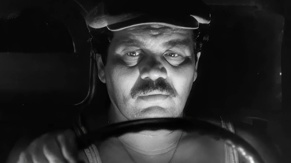 Luigi, played by actor Fulco Lulli, sat behind the wheel of a vehicle in deep shadow in The Wages of Fear.