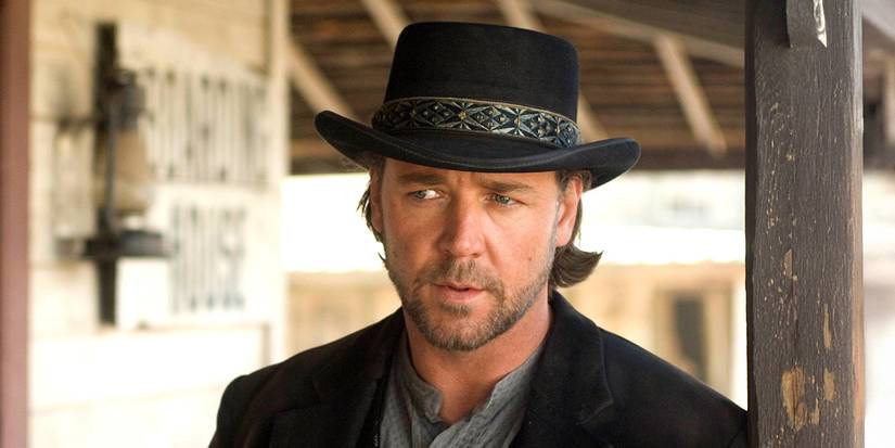 Russell Crowe wearing a cowboy hat and standing outside an old western building in 3:10 to Yuma.