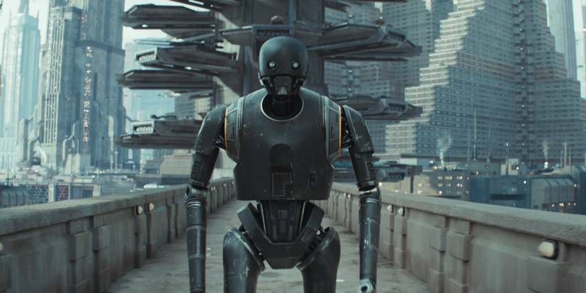 K-S2O (Alan Tudyk) walks over a bridge in a built-up city area in 'Andor' (2022-2025).