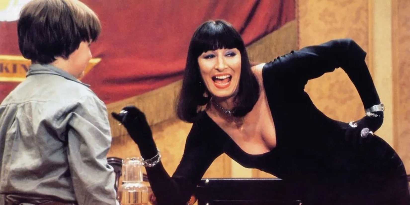Anjelica Huston as The Grand High Witch laughs as she talks to a child in The Witches.