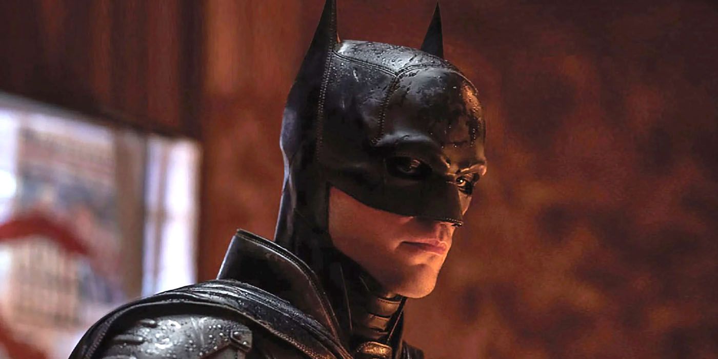 Robert Pattinson sebagai Batman melihat ke bawah pada sesuatu di tengah hujan di The Batman.