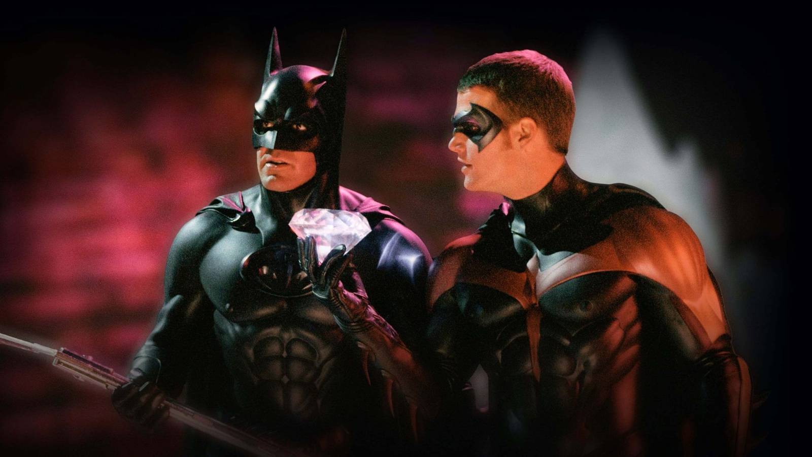 Batman (George Clooney) stands next to Robin (Chris O'Donnell) who holds a large diamond in Batman & Robin