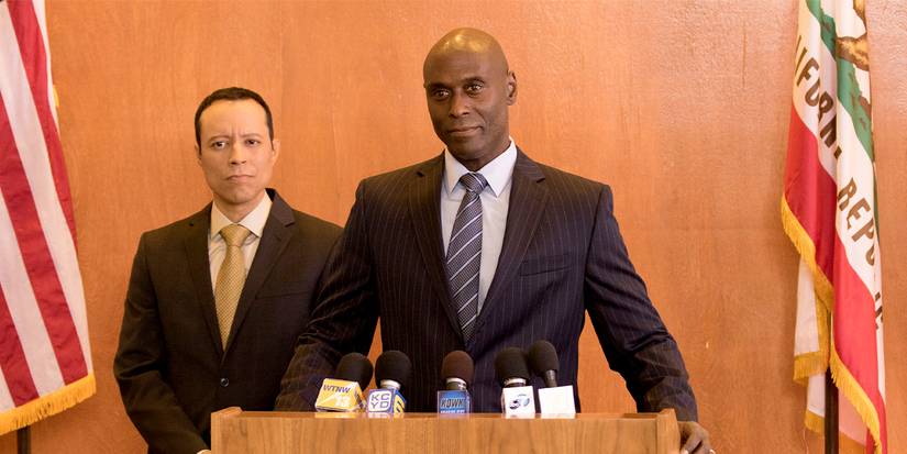 Lance Reddick at a podium with microphones in Bosch.