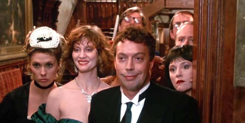 Tim Curry and Lesley Ann Warren standing in a doorway as other characters group up behind them in Clue.