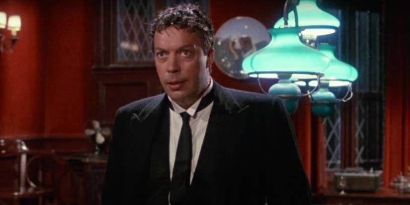 Tim Curry as Wadsworth the butler standing in a billiards room while soaking wet in Clue.