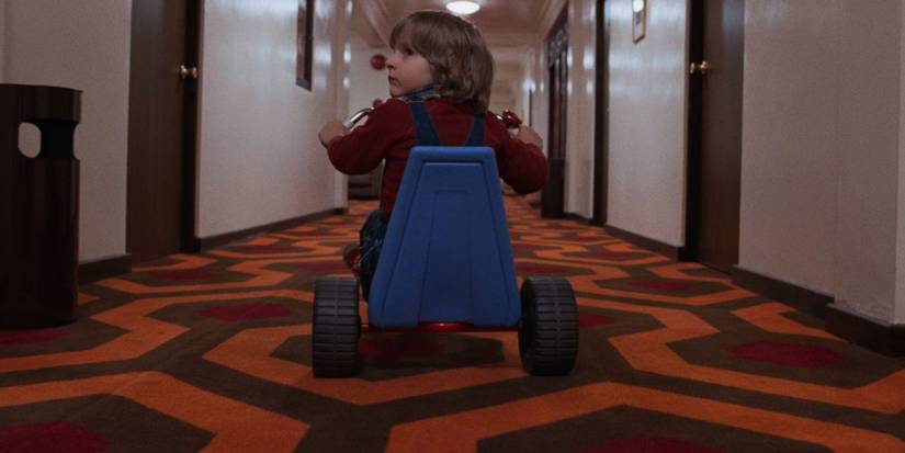 Danny pauses his tricycle ride to look over his shoulder in The Shining