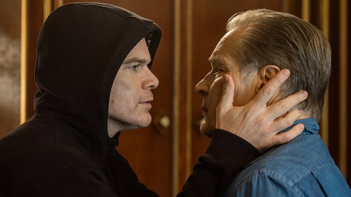 Dexter wearing a black hoodie, holding his father's face in Dexter: Resurrection.