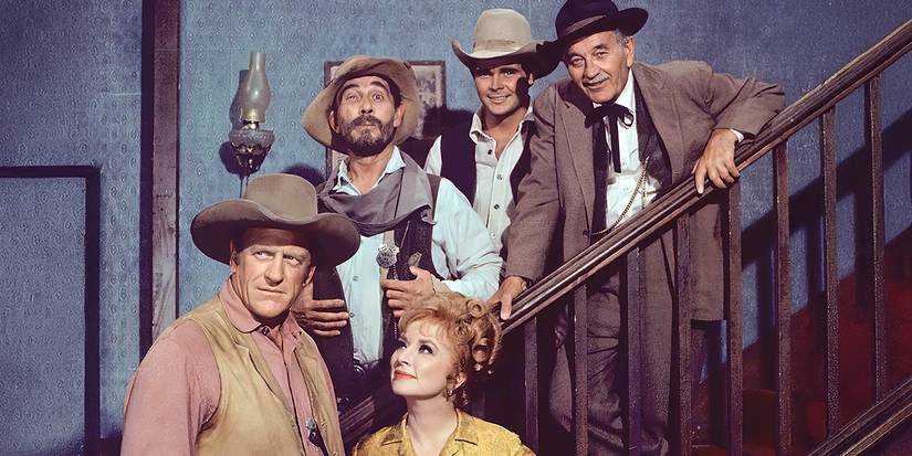 The cast of Gunsmoke smiling on the steps in a promo shot.