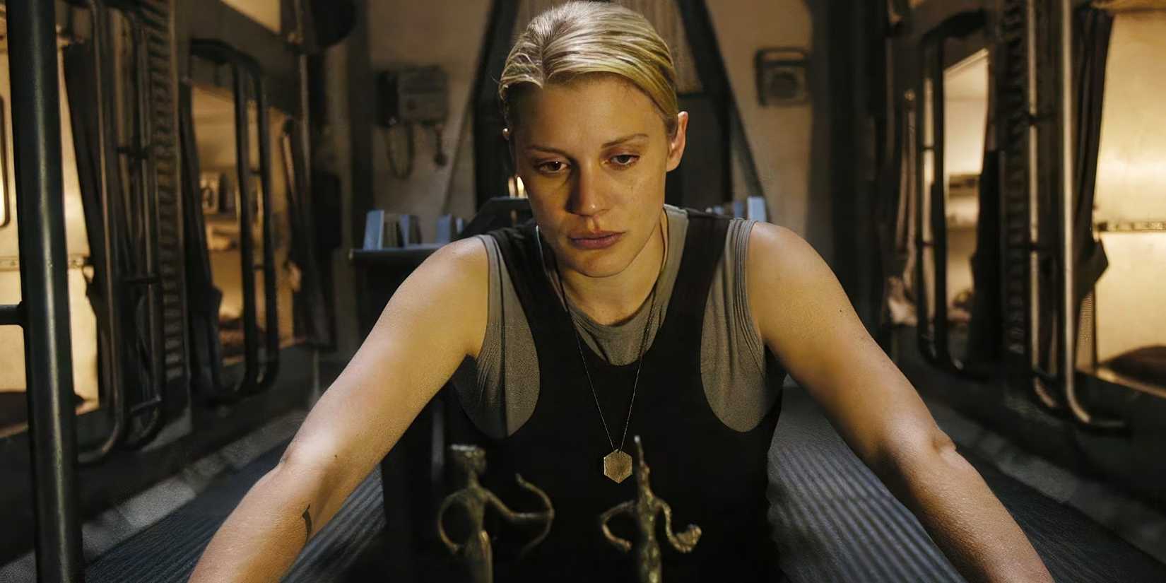 Katee Sackhoff sitting down and looking serious in Battlestar Galactica.