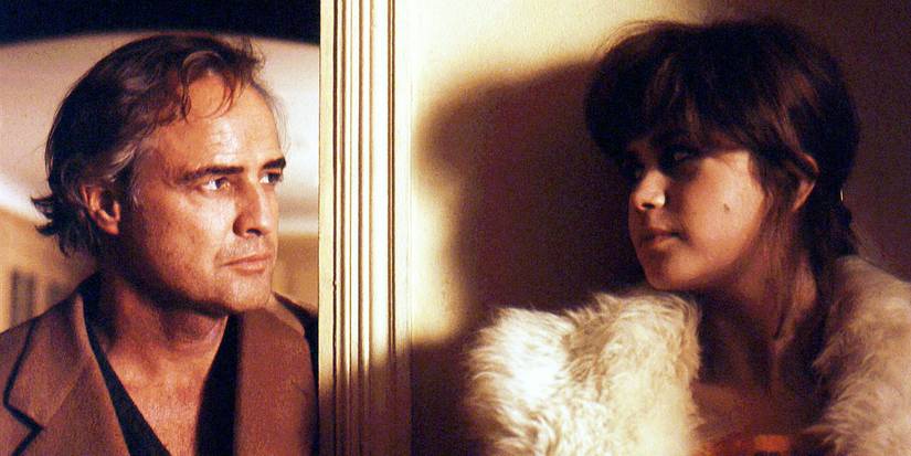 the two lovers look at one another in a hotel room, against the door in Last Tango in Paris