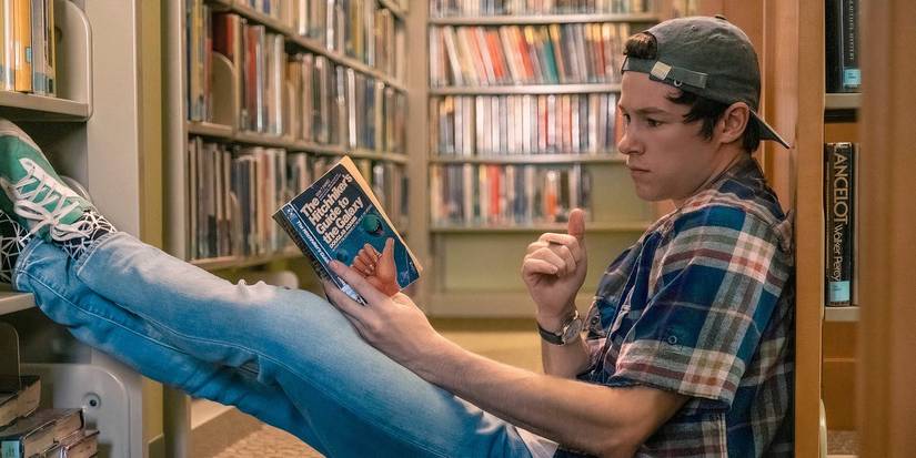 Kyle Allen as Mark reading a book at a library floor in The Map of Tiny Perfect Things