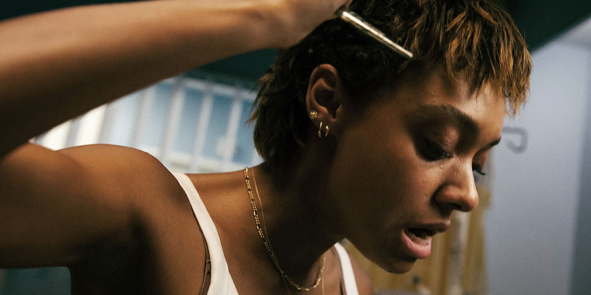 A young woman raises a small weapon (scissors) over her head in Talk to Me