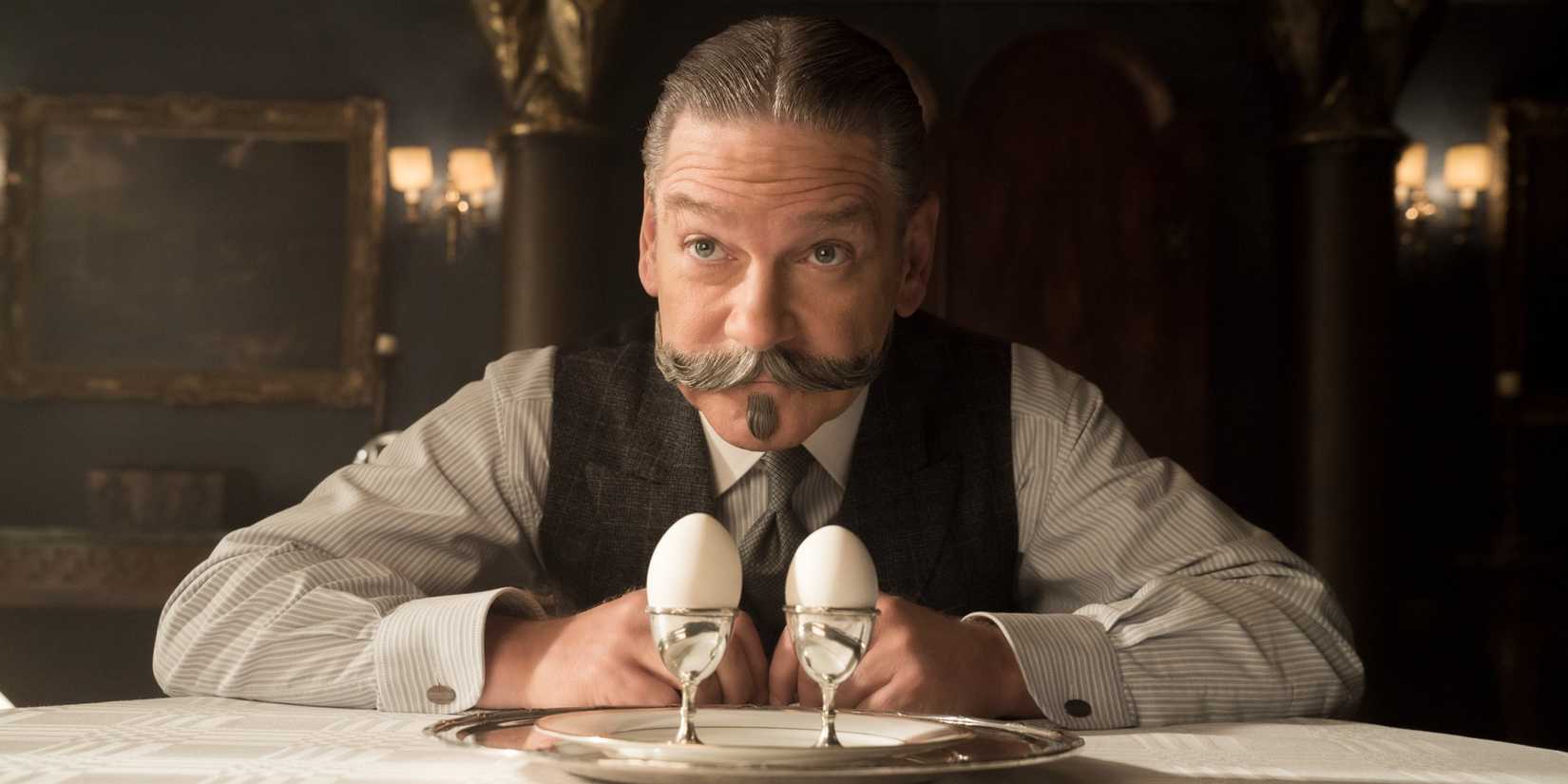 Kenneth Branagh sits behind his desk with two eggs on it in Murder on the Orient Express