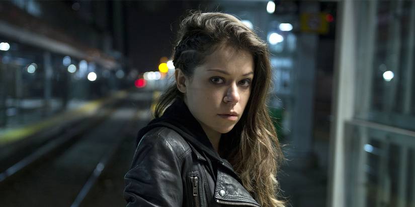 Tatiana Maslany in a leather jacket looking at the camera at a train station in Orphan Black.