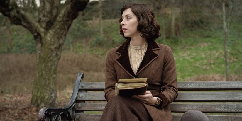 Hermione Corfield writing a letter on a park bench in Outlander: Blood of My Blood.