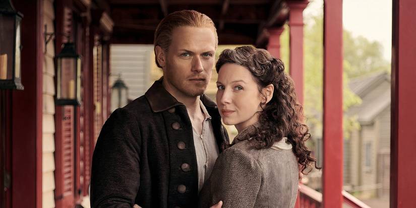 Caitríona Balfe as Claire and Sam Heughan as Jamie looking at the camera in Outlander.