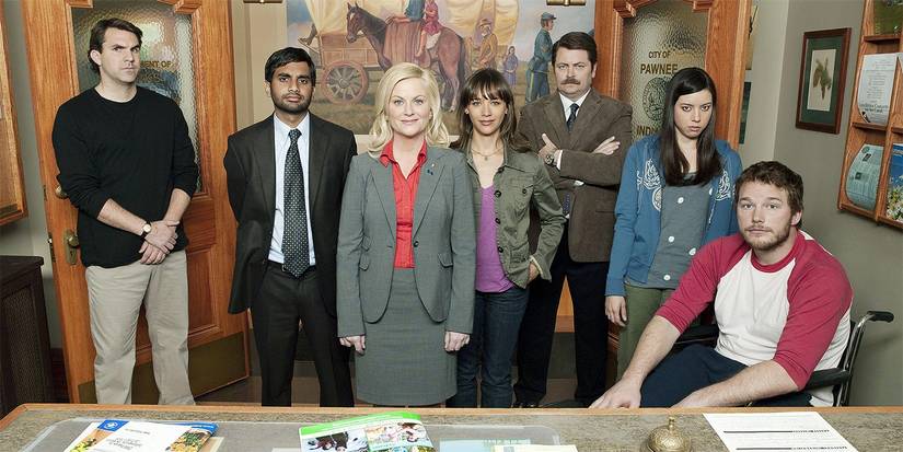 The cast from Season 1 of Parks and Recreation in the office looking at the camera.