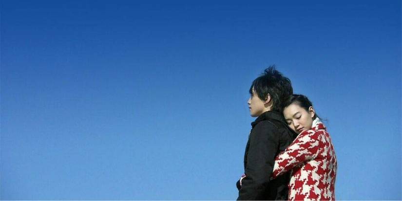 Shin Min-a holding Rain from behind against a blue sky backdrop in A Love to Kill