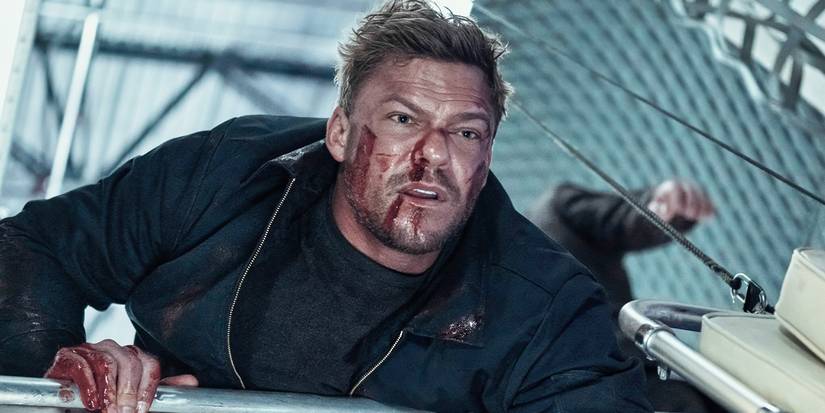 Alan Ritchson as Jack Reacher, looking down from a height with a wounded face in Reacher.