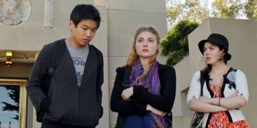 Ki Hong Lee, Skyler Samuels, Grace Phipps as Paul, Chloe, and Amy standing outside school wearing a grey hoodie, black jacket, and hat in 'The Nine Lives of Chloe King.'