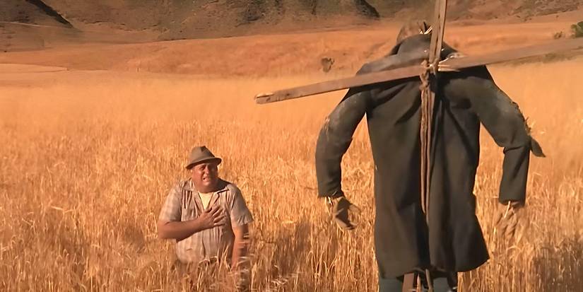 A man kneels down and is scared of a creepy scarecrow in the TV movie Dark Night of the Scarecrow.