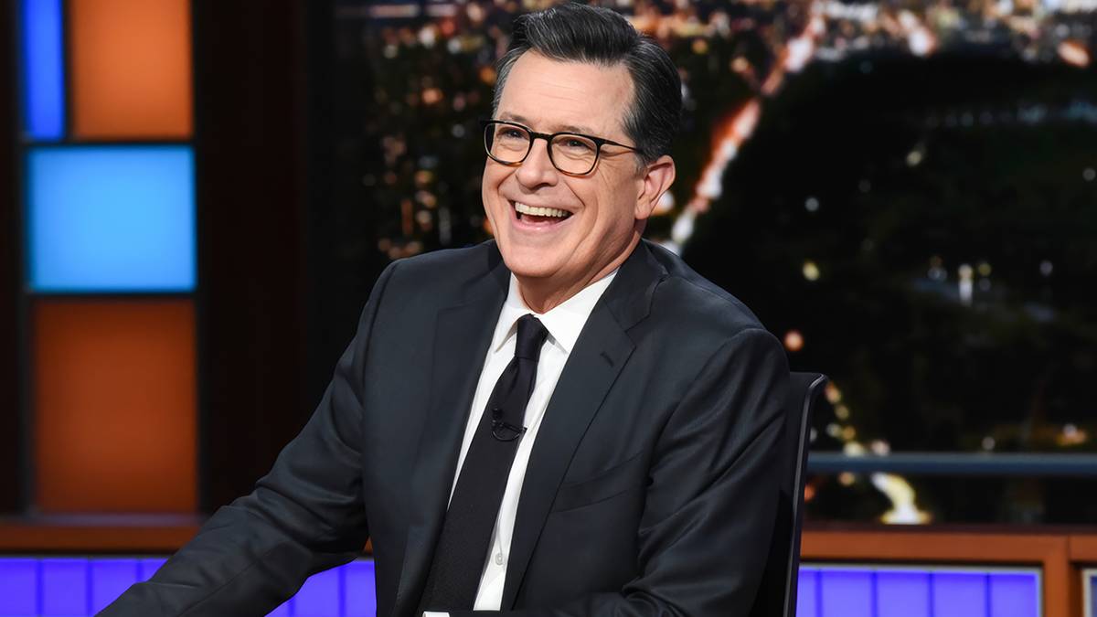 Stephen Colbert smiling behind his desk on 'The Late Show with Stephen Colbert.'