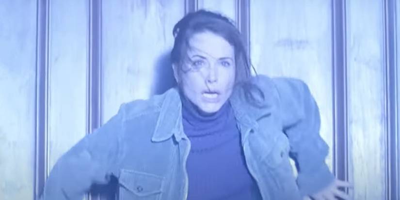 Debrah Farentino bracing herself against a wall bathed in bright white light in Storm of the Century.