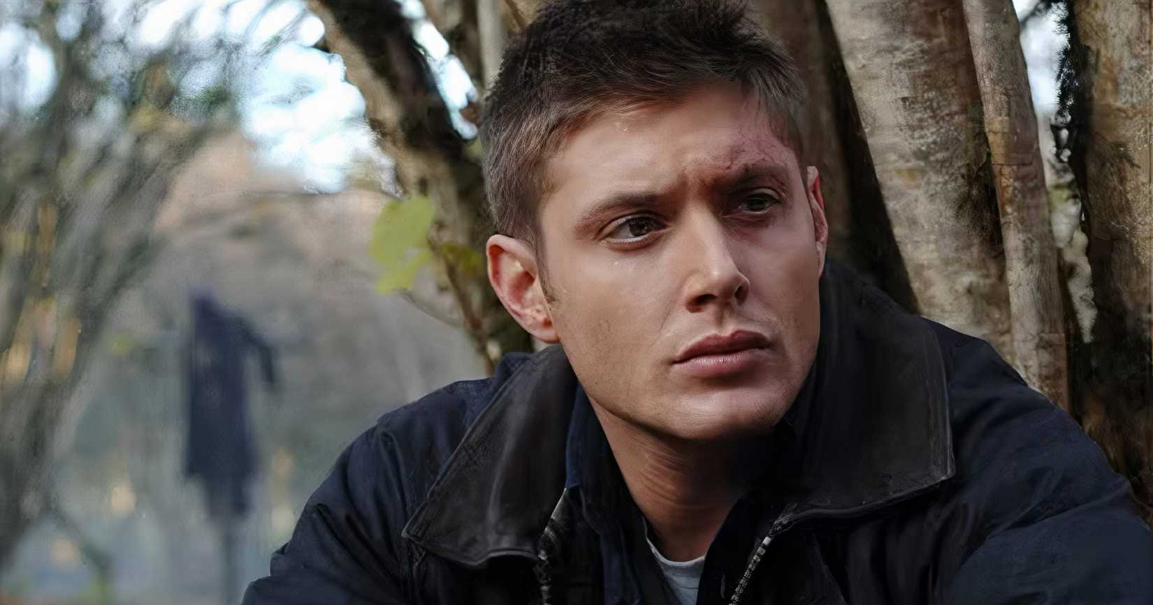 Dean Winchester (Jensen Ackles) in the woods with a scarecrow behind him in the "Scarecrow" episode of 'Supernatural'