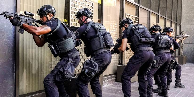 Team of SWAT officers in tactical gear aim guns in various directions