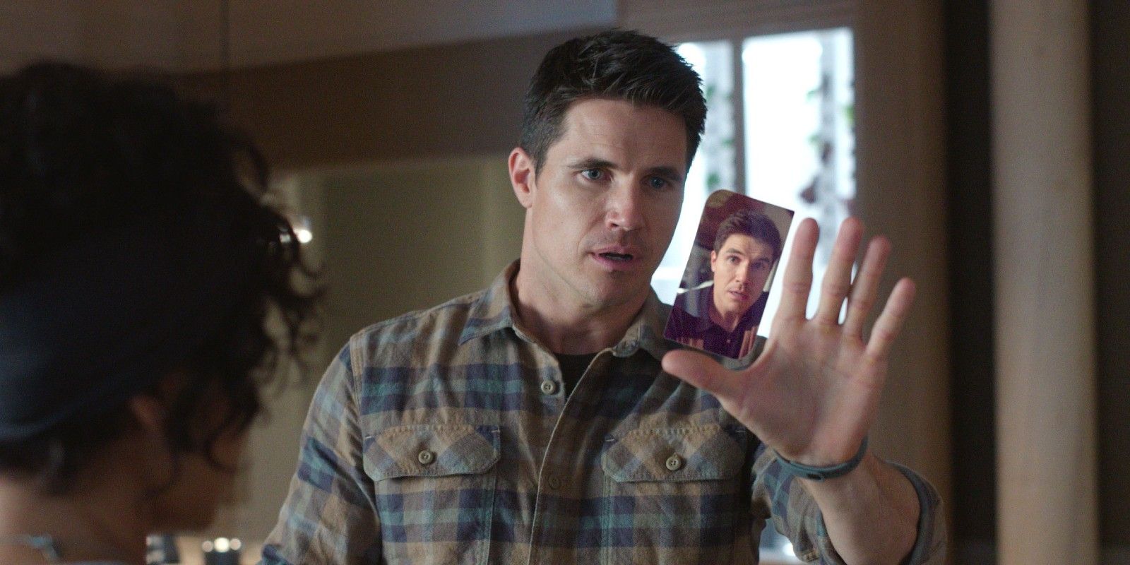 Robbie Amell holds out a hand with another smaller version of him in Upload Season 4