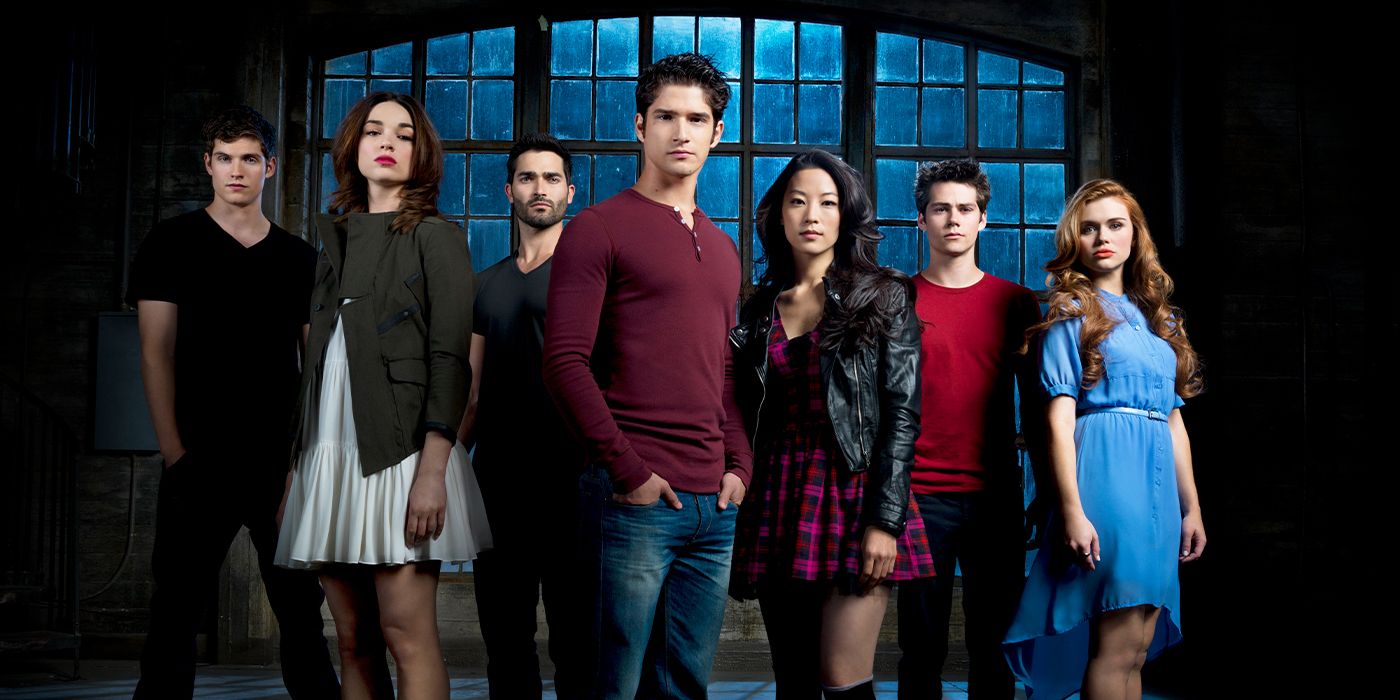 The cast of Teen Wolf standing in front of a large window and looking at the camera.