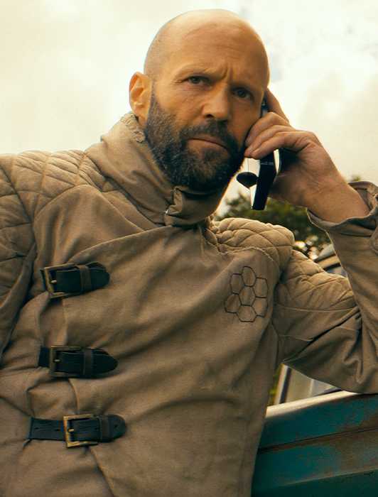 Jason Statham as Adam Clay on a cell phone near his beat-up car in The Beekeeper (2024)