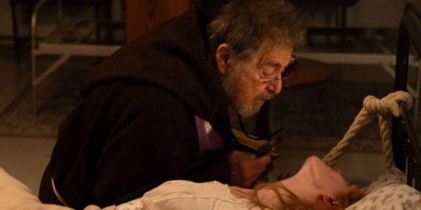 A priest leans over a possessed girl tied to a bed in The Ritual