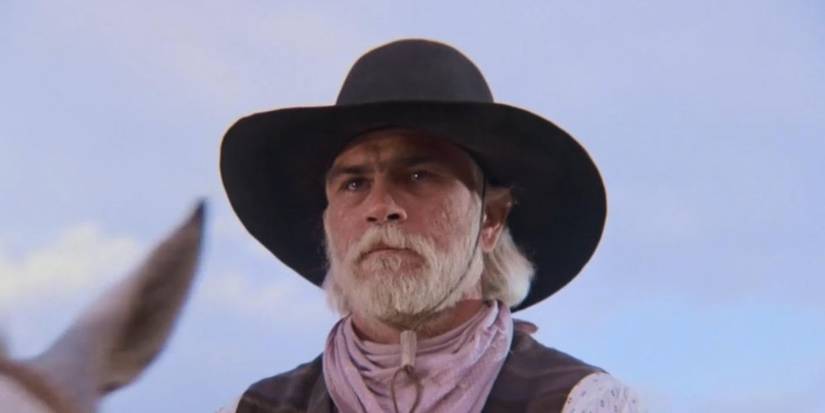 Tommy Lee Jones with white hair and beard wearing a hat and riding a horse in Lonesome Dove.