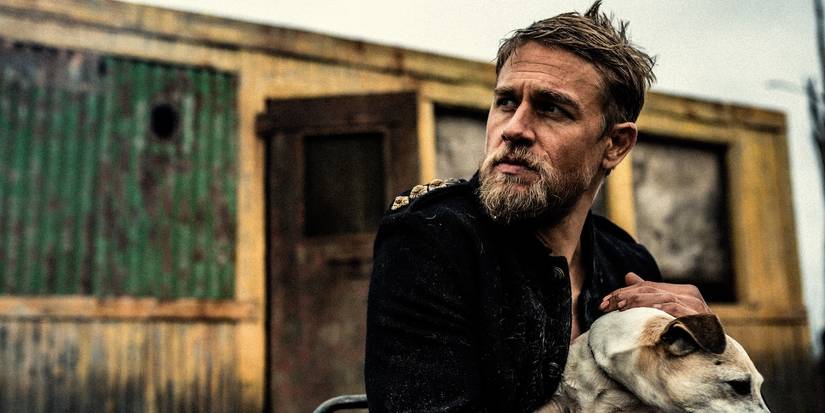 Charlie Hunnam petting a dog and looking to the side in True History of the Kelly Gang.