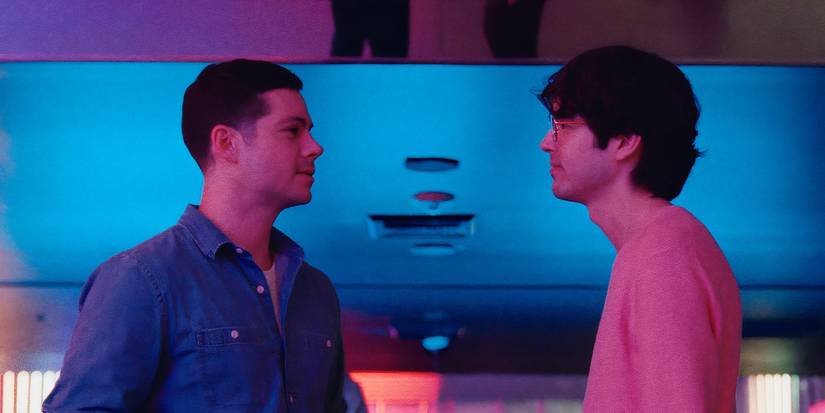 Actors Dylan O'Brien and James Sweeney as Roman and Dennis, standing face to face in a nightclub in Twinless
