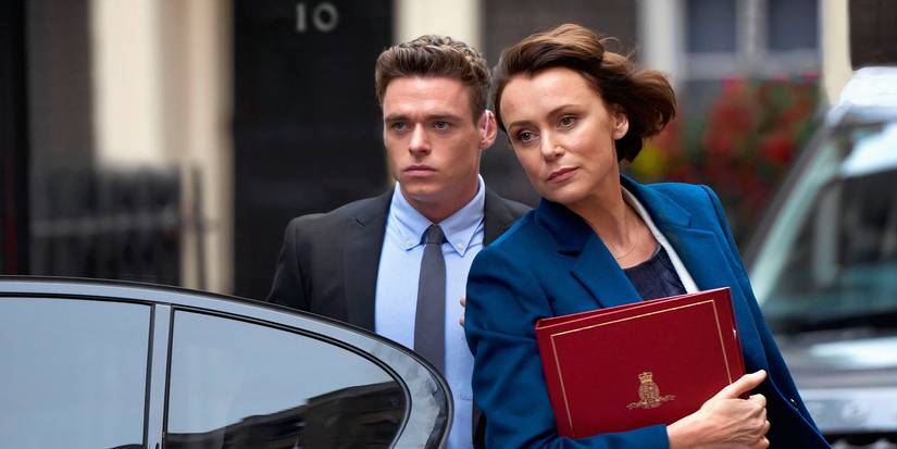 A man in a suit escorts a woman with a binder into a car in a scene from Bodyguard.