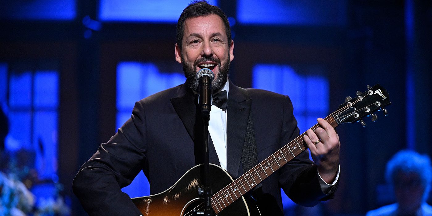 Adam Sandler smiling with a guitar during the SNL50.