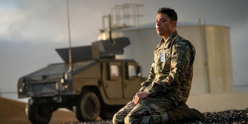Anthony Ramos sitting on his knees in a army uniform near a jeep in House of Dynamite.