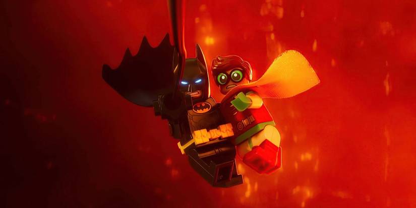 Batman swings on a rope holding Robin, who looks scared in The Lego Batman Movie.