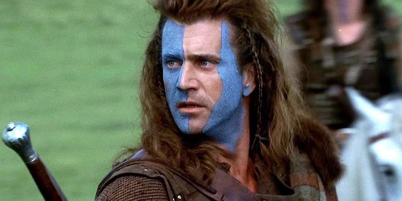 Mel Gibson with long hair and blue face paint on a battlefield in Braveheart.