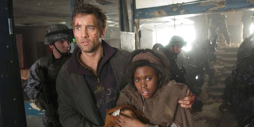 Clive Owen holding Clare-Hope Ahitey as they walk through a crowd in Children of Men