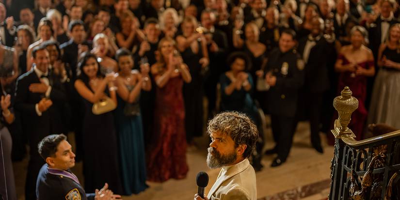 Leon at his gala standing in front of a crowd of police officers with a microphone in Dexter: Resurrection.