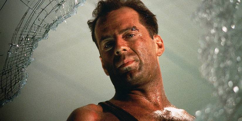Bruce Willis as John McClane looking down through a broken glass window in Die Hard, 1988.