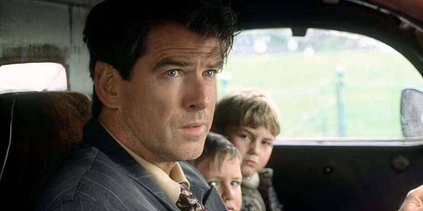 Pierce Brosnan sentado em um carro com dois filhos sentados ao lado dele em Evelyn (2002).