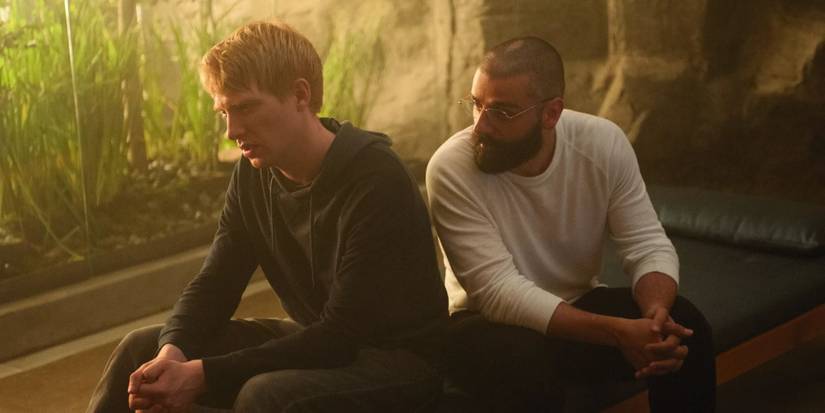 Domhnall Gleeson and Oscar Isaac sitting near each other and talking in Ex Machina.