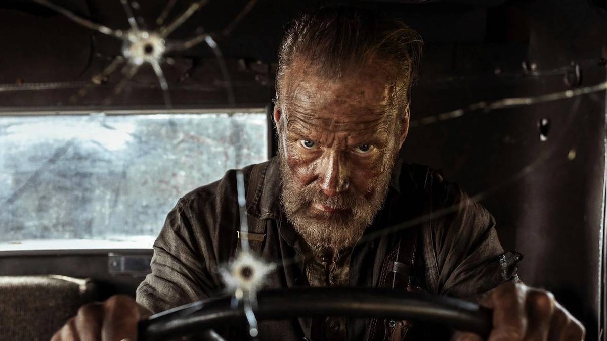 Jorma Tommila driving a vehicle with bullet holes on the windshield in Sisu: Road to Revenge